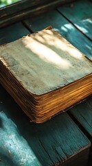 Old book with yellowed pages lies on wooden surface, sun streaming in window