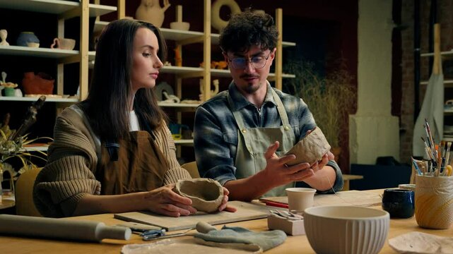 Caucasian man potter artist help woman pottery workshop modeling clay study sculpture creative love date in art studio teacher student create handmade ceramics pot design girl guy teaching crockery