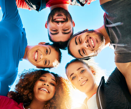 Happy people, portrait and below with huddle for fitness, teamwork or mission together under blue sky. Low angle, active group or circle with community in solidarity for unity, health and wellness