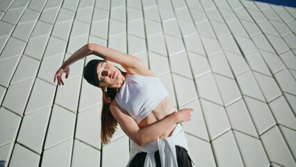 Athletic woman bending body practicing fitness exercises on sunny street closeup