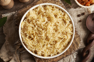 Homemade fermented cabbage or sauerkraut in a bowl on a wooden table