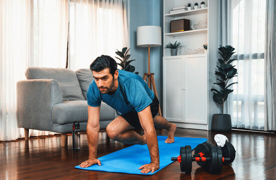 Athletic and sporty man doing mountain climber on fitness mat during home body workout exercise session for fit physique and healthy sport lifestyle at home. Gaiety home exercise workout training.