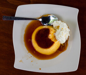 Top view of tasty sweet custard flan with air whipped cream and caramel topping..