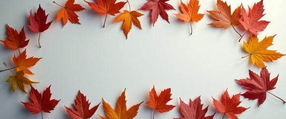 Fototapeta premium A stunning array of autumn leaves in fiery shades of red, orange, and yellow forms a beautiful oval frame against a soft, neutral background. This captivating composition evokes the warmth and beauty