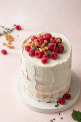 Semi naked red velvet cake with cream cheese frosting decorated with fresh raspberries and currants. Festive layered sponge cake. Traditional American dessert. Selective focus.