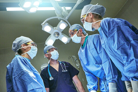 Low angle, surgery and team of doctors in hospital for emergency crisis, medical service and procedure. Healthcare, discussion and surgeons with patient pov for injury, operation and ICU treatment