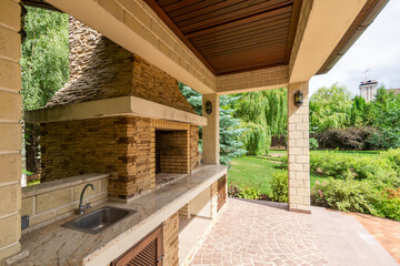 Gazebo with barbecue oven on a private territory, against a beautiful landscape on a clear sunny day.