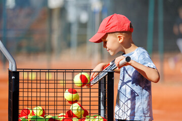 Cute little happy kid boy enjoy collecting balls in basket cart sign plate Kids-training clay...