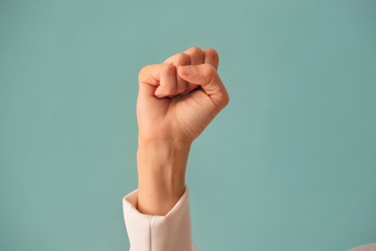 International Women's Day 2025: Accelerate Action. Woman hand gesture signifying achievement of gender equality and empowerment. Female hand with clenched fist on blue color background