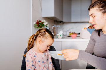 Cute little girl wearing pajamas refusing to eat her breakfast at home