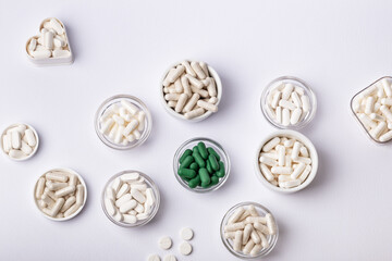 Dietary supplements, vitamins and minerals in small plates on white background. Happy and healthy lifestyle. Thite and green tablets. Top view.