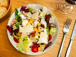 Delicious fresh caesar salad with parmesan and sliced chicken served on plate