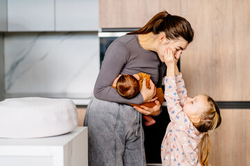 Toddler girl, 3 years old, laughs and plays, stroked mom holding a newborn. Genuine moments of...