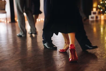 Dancing stiletto shoes of couples dancing traditional latin argentinian dance milonga in the ballroom, tango salsa bachata kizomba lesson in red and purple lights, evening dance school class festival