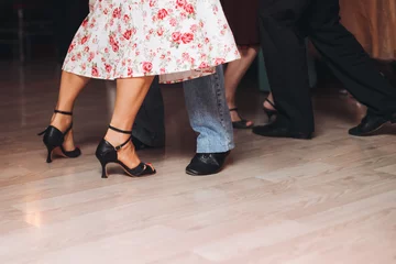 Dancing stiletto shoes of couples dancing traditional latin argentinian dance milonga in the ballroom, tango salsa bachata kizomba lesson in red and purple lights, evening dance school class festival