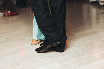 Dancing stiletto shoes of couples dancing traditional latin argentinian dance milonga in the ballroom, tango salsa bachata kizomba lesson in red and purple lights, evening dance school class festival