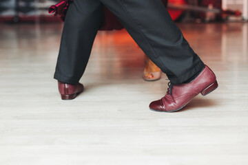 Dancing stiletto shoes of couples dancing traditional latin argentinian dance milonga in the ballroom, tango salsa bachata kizomba lesson in red and purple lights, evening dance school class festival