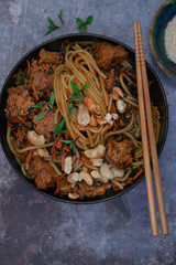 Vegan noodles and seitan stir fry on gray table, copy space