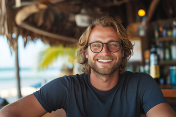 Smiling man in casual attire relaxes at beachside bar enjoying tropical atmosphere during sunny day
