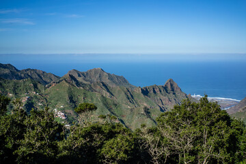Naklejka premium Stunning view of lush green mountains cascading down to the vibrant blue ocean in Tenerife.