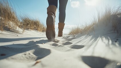 A captivating close-up view of a person walking along a sandy beach path, surrounded by tall grass under a bright, sunlit sky, evoking feelings of joy and adventure during summer travels.
