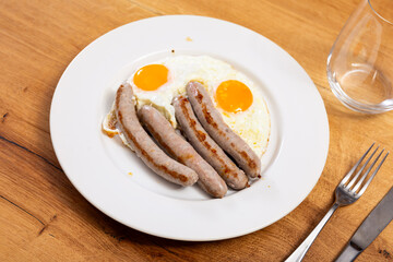 Delicious fried eggs with sausage served on platter for breakfast