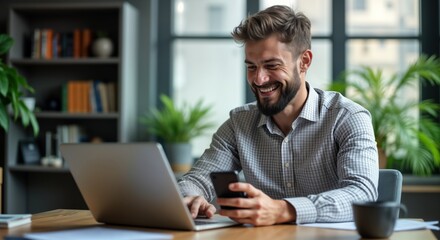 Smiling businessman sits at desk using laptop, mobile phone. Happy entrepreneur working in office. Modern tech lifestyle. Business communication, success. Pro man engaged in productive work.