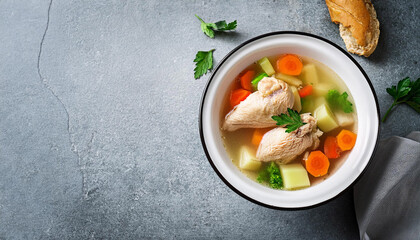 chicken soup with vegetables in white bowl grey stone background copy space