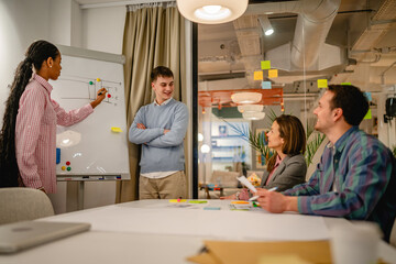 two multicultural male and female explain their strategy on white board