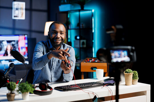 African american technology internet star filming review of newly released USB wired RGB lights mouse. Man giving audience feedback about computer peripheral power, doing endorsement