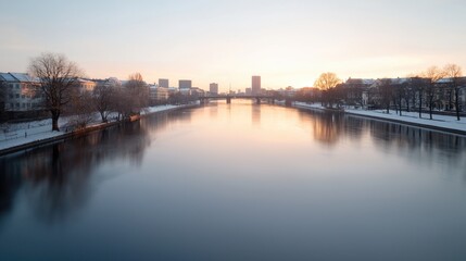 Naklejka premium Winter sunrise over river, city skyline, calm water, snowy banks