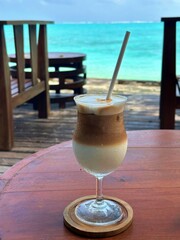ice latte on a wooden table looking into the sea