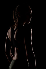 Silhouette of a Strong Woman's Back Showcasing Muscular Definition in Low Light