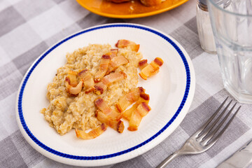 Delicious oatmeal porridge served with fried lard on platter