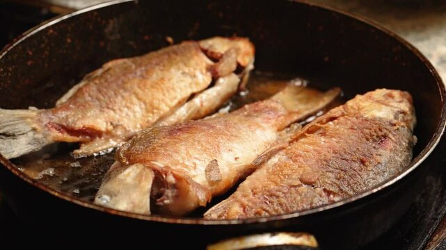 Home cooking. River fish crucian carp is fried in a frying pan in sunflower oil