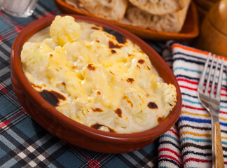 Dish of tasty baked with bechamel sauce cauliflower at clay pot