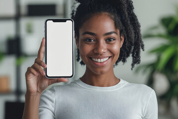 Cheerful African young woman in a business suit holding and showing us a smartphone with a blank white screen, standing in a modern office environment, looking happy. Phone mockup