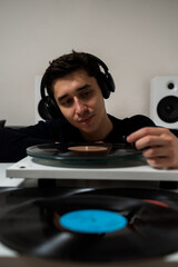 Musician listens a vinyl album collection on a needle player. Music lover puts a vinyl record on needle player before listening retro music. LP record playing on a turntable.