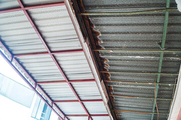 Fototapeta premium Image shows a severely damaged ceiling, revealing rusty metal supports and broken plaster. Urgent repair is required. Damaged Ceiling Structure: Urgent Repair Needed