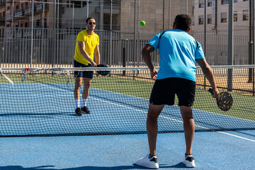 Obraz premium Two male athletes playing pickleball on a sunny day