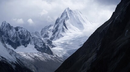 Majestic snow-capped mountains pierce a cloudy sky creating a dramatic landscape view