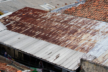 Close-up view of rusty and weathered corrugated metal roofs. Showing signs of age and decay, revealing industrial texture. Rusty and Weathered Corrugated Metal Roofs in Urban Setting