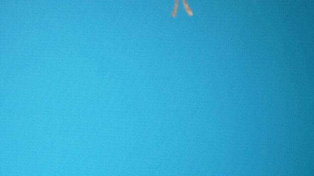 Doctor uses scissors to cut the rope that holds two eggs in a plastic bag on a blue background, close up. The concept of vasectomy and men's health. Idea about male testicular health