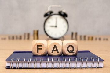 text FAQ on wooden cubes on office table with o'clock and coins, Frequency Asked Questions concept
