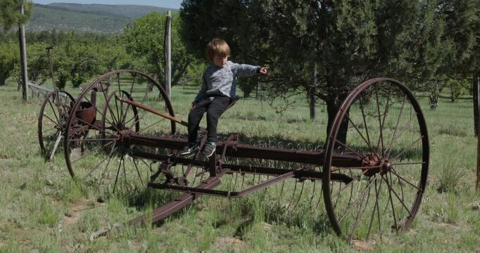 Little Boy Playing on Old Farm Equipment