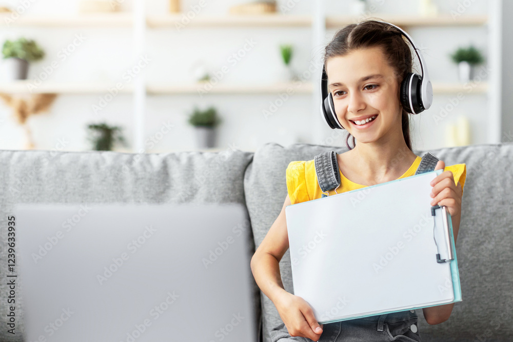 Poster Smiling girl having video call with teacher, holding flipchart with paper showing done task result using laptop. Child studying remotely. Creativities lessons, homeschool