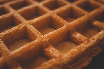 Golden-brown crispy waffles in a close-up shot. Detailed texture with a crisp outer layer and soft interior. Freshly baked breakfast food with a warm and inviting appearance