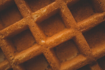 Golden-brown crispy waffles in a close-up shot. Detailed texture with a crisp outer layer and soft...