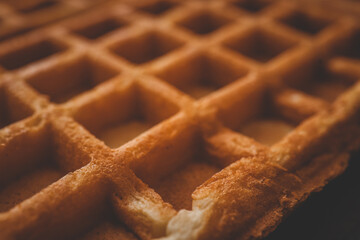 Golden-brown crispy waffles in a close-up shot. Detailed texture with a crisp outer layer and soft interior. Freshly baked breakfast food with a warm and inviting appearance