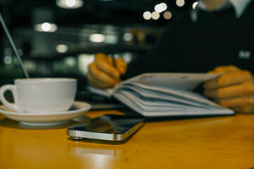 A professional workspace with a person organizing tasks using a notebook, tablet, and laptop on a wooden table, creating a productive and modern office environment